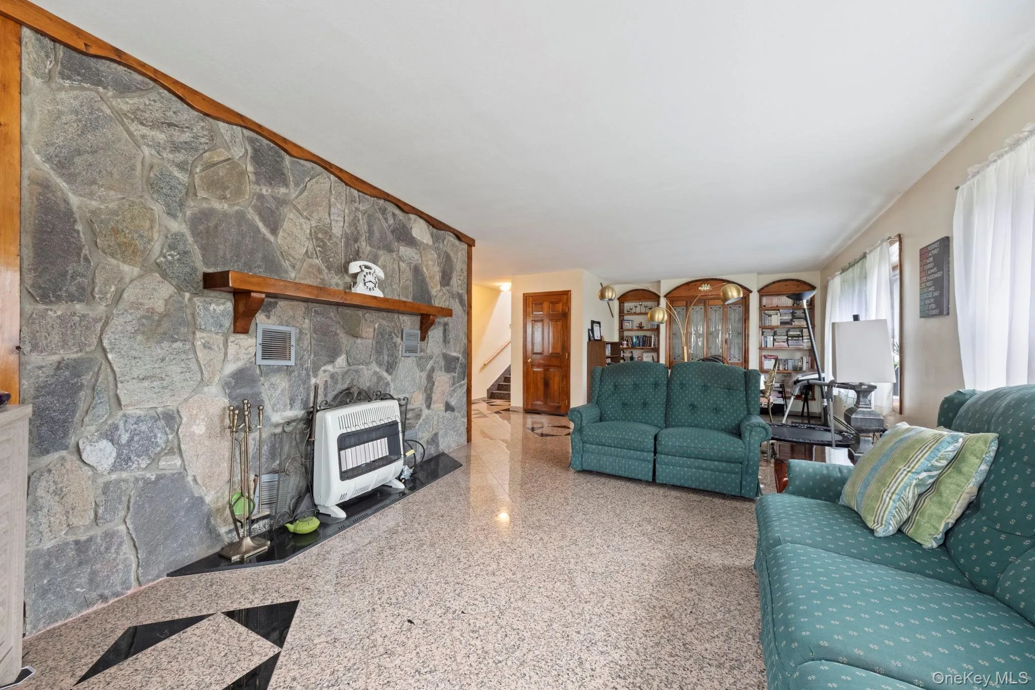 Living room featuring heating unit, stairs, and speckled floor Living room featuring heating unit, stairs, and speckled floor