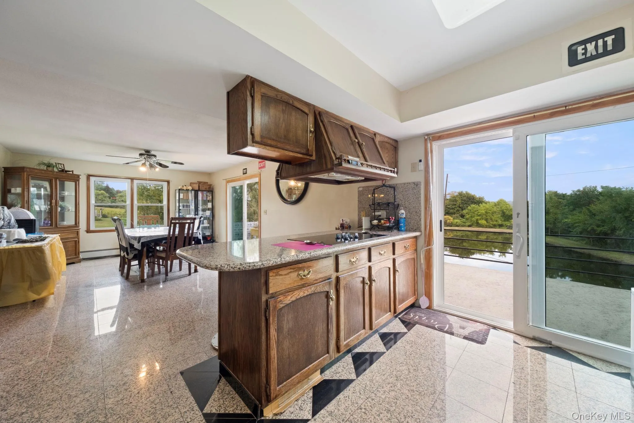 Kitchen featuring granite floors, a peninsula, under cabinet range hood, a ceiling fan, and light stone counters Kitchen featuring granite floors, a peninsula, under cabinet range hood, a ceiling fan, and light stone counters