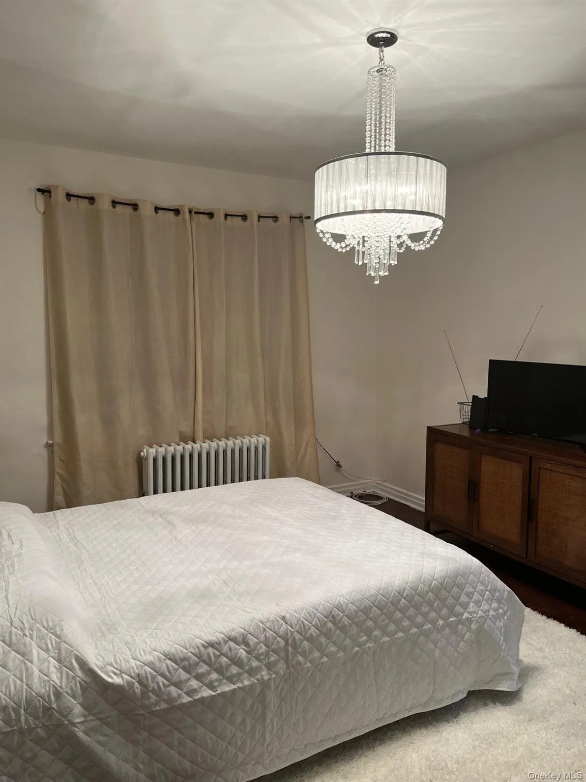 Bedroom with radiator heating unit and a chandelier Bedroom with radiator heating unit and a chandelier