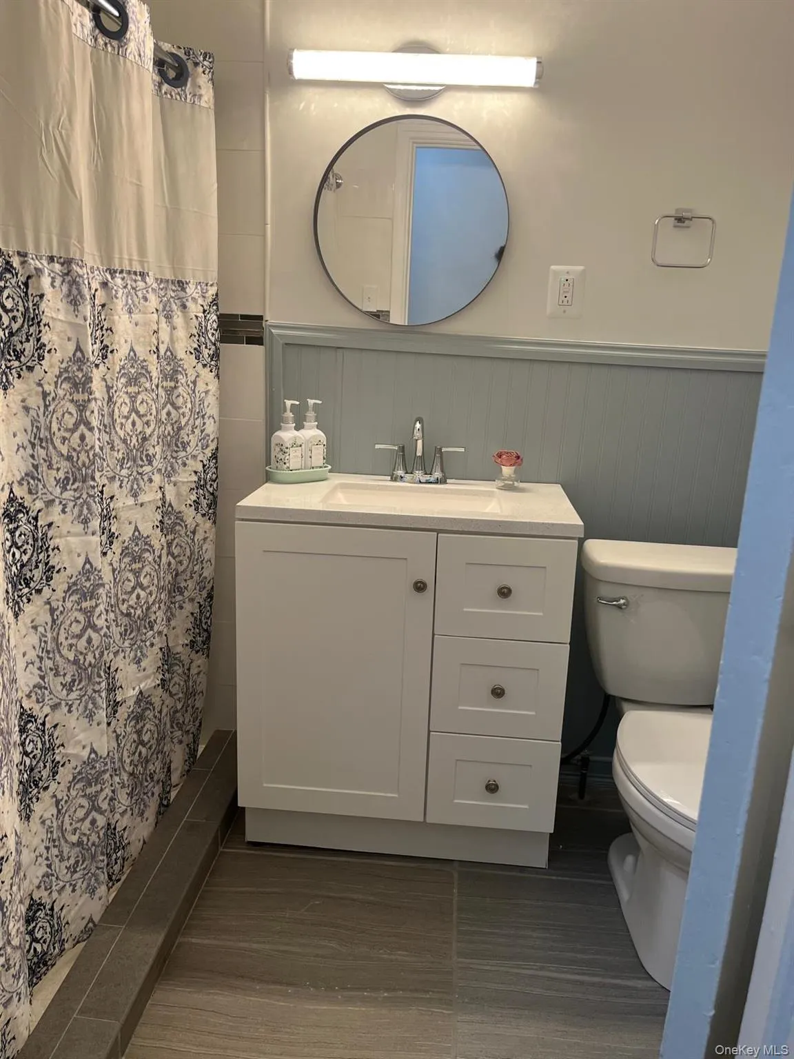 Full bath featuring vanity, a stall shower, and a wainscoted wall Full bath featuring vanity, a stall shower, and a wainscoted wall