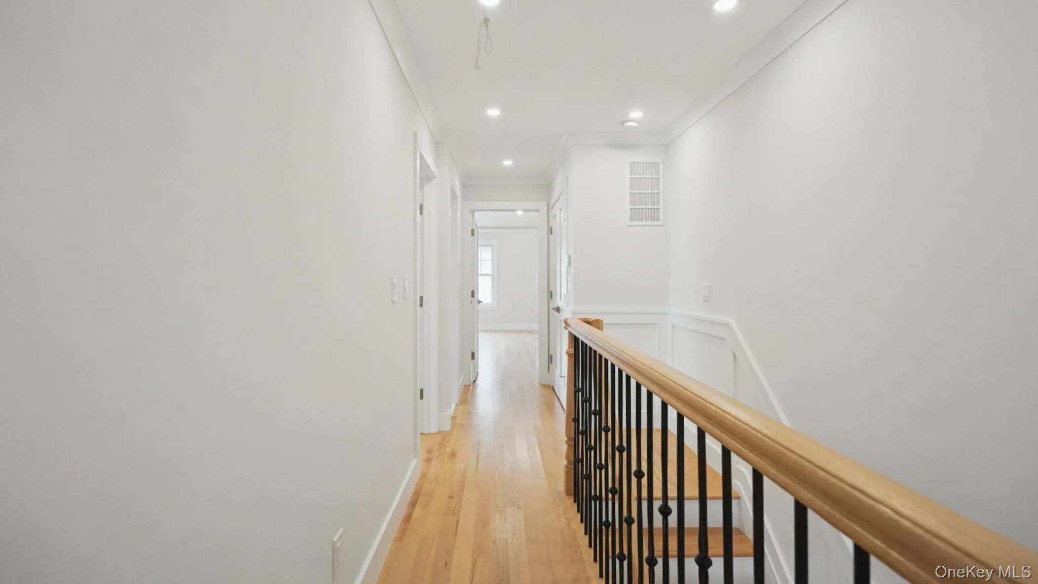 Hall featuring light wood finished floors, an upstairs landing, recessed lighting, and ornamental molding Hall featuring light wood finished floors, an upstairs landing, recessed lighting, and ornamental molding