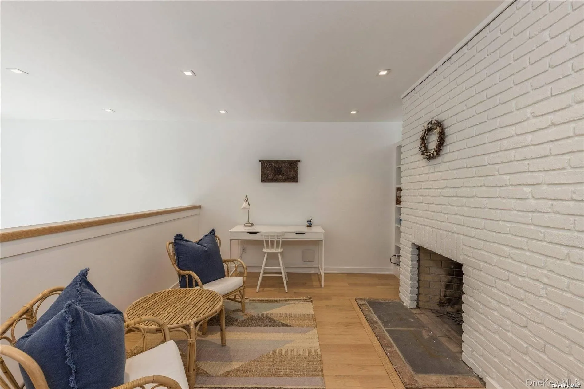 Sitting room featuring light wood-style flooring, brick wall, a fireplace, and recessed lighting Sitting room featuring light wood-style flooring, brick wall, a fireplace, and recessed lighting