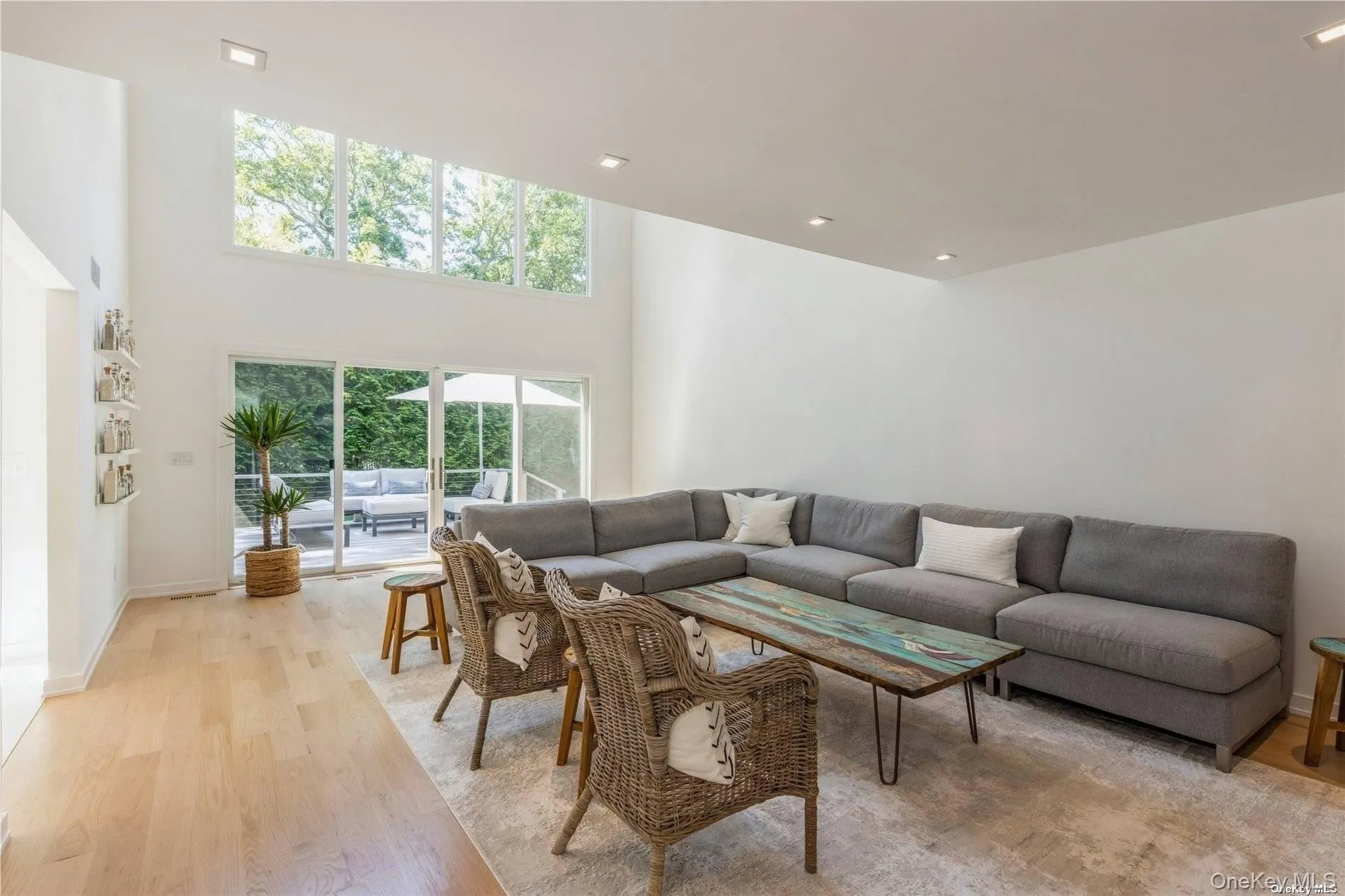 Living area featuring light wood-style flooring, a towering ceiling, and recessed lighting Living area featuring light wood-style flooring, a towering ceiling, and recessed lighting