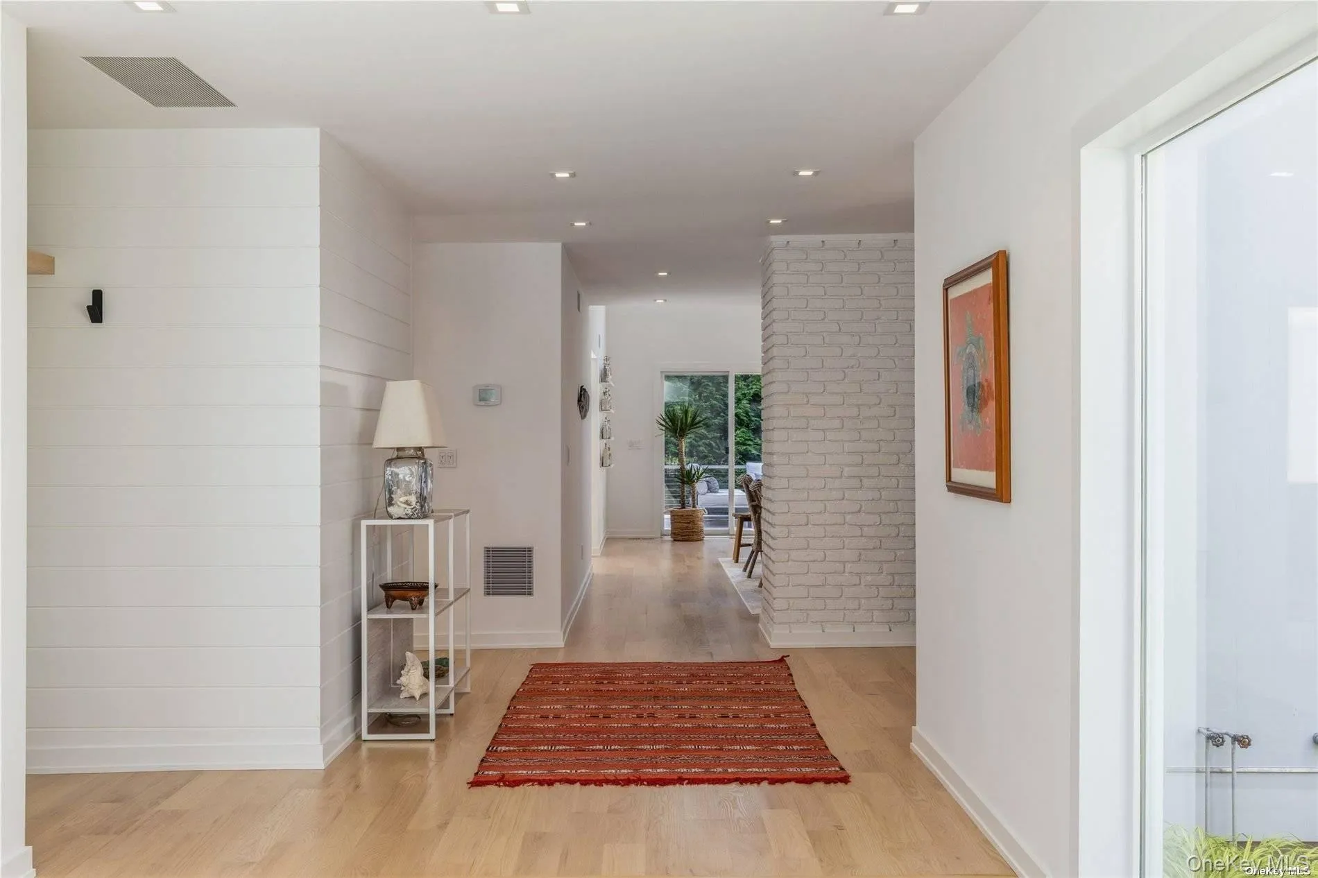 Hallway featuring light wood-type flooring, recessed lighting, and brick wall Hallway featuring light wood-type flooring, recessed lighting, and brick wall