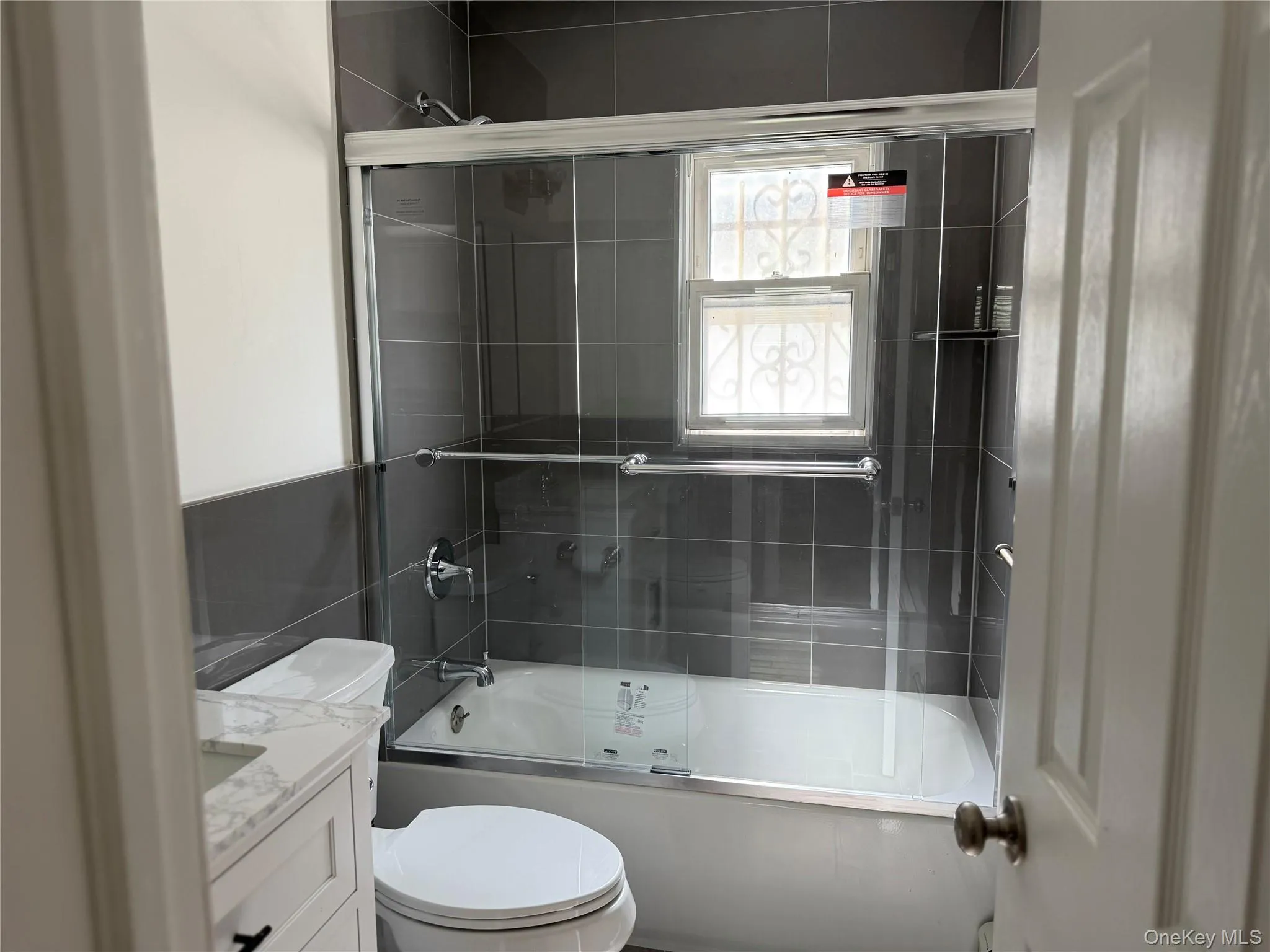 Full bathroom featuring bath / shower combo with glass door and vanity Full bathroom featuring bath / shower combo with glass door and vanity