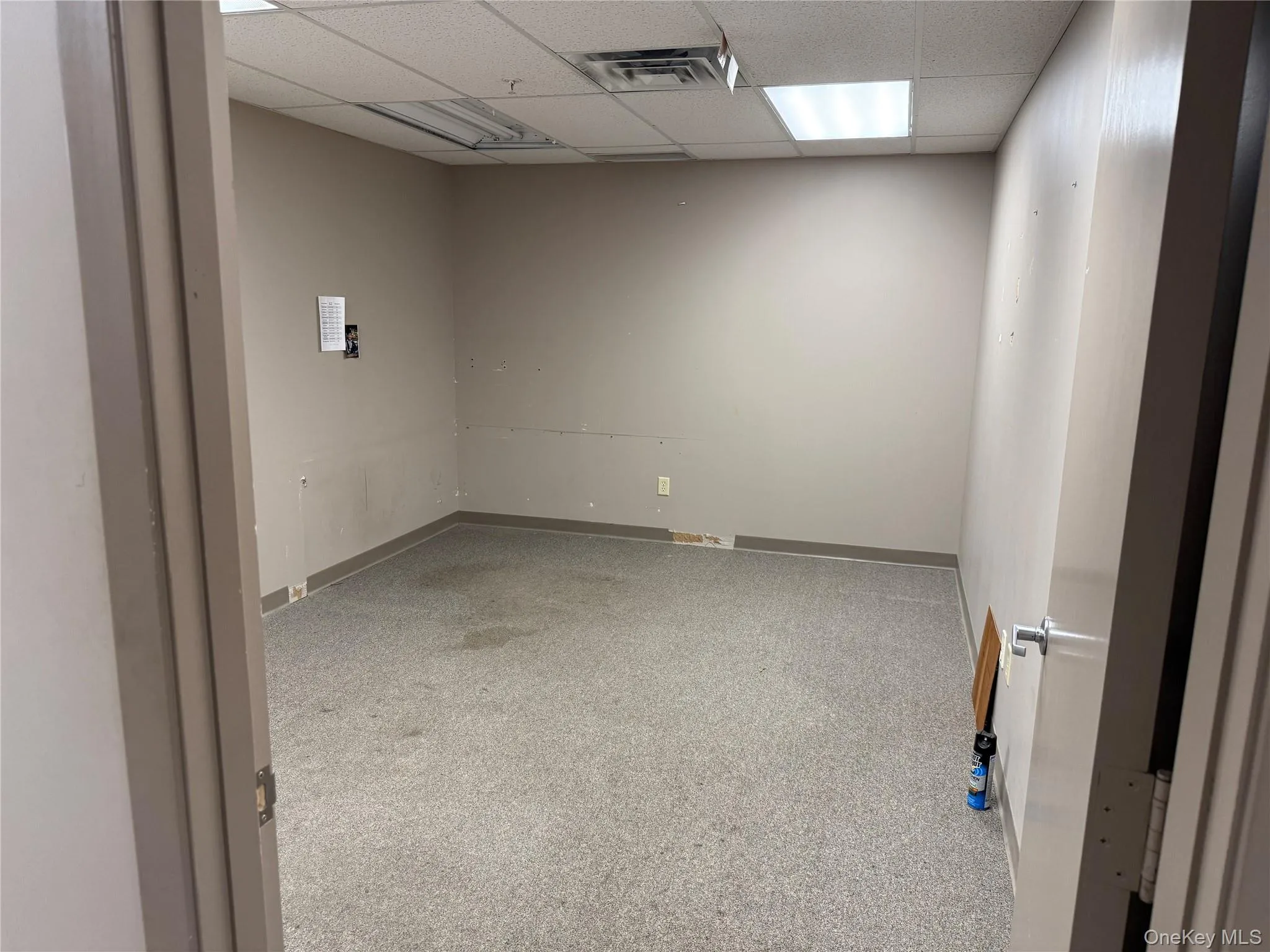 Unfurnished room with baseboards and a drop ceiling Unfurnished room with baseboards and a drop ceiling