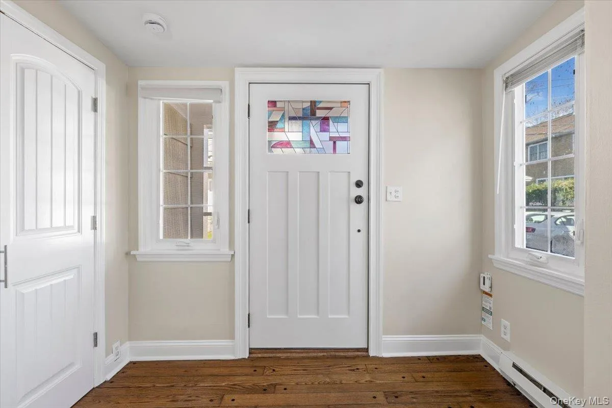 Foyer featuring a baseboard heating unit and dark wood-style flooring Foyer featuring a baseboard heating unit and dark wood-style flooring
