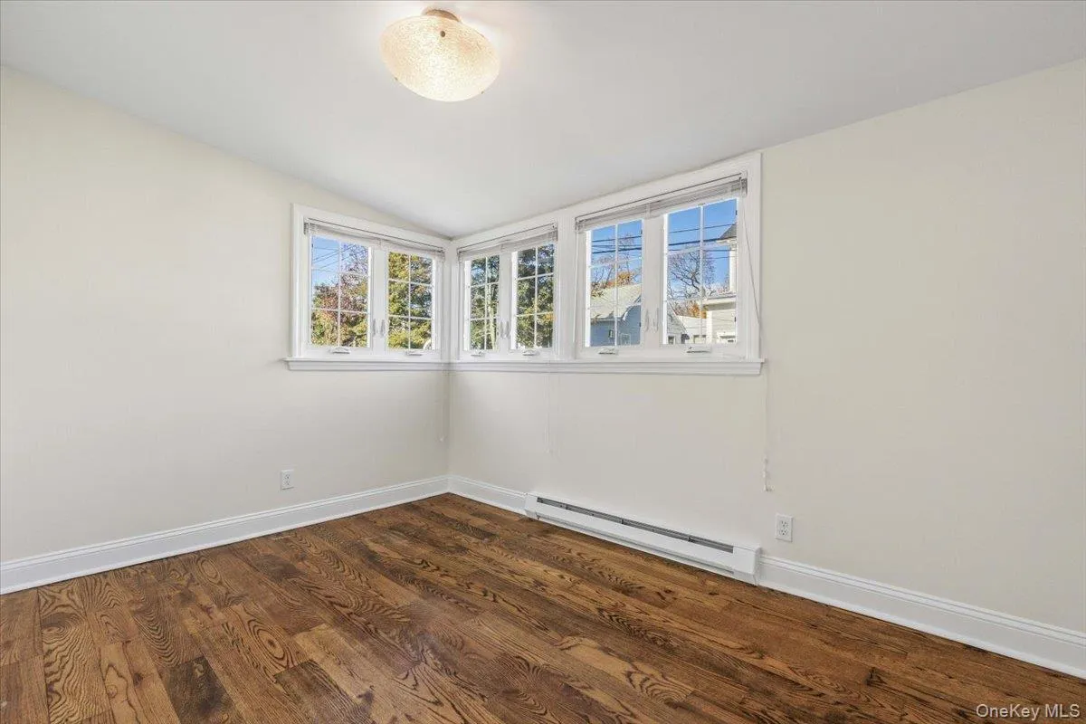 Spare room with a baseboard radiator, dark wood finished floors, and vaulted ceiling Spare room with a baseboard radiator, dark wood finished floors, and vaulted ceiling