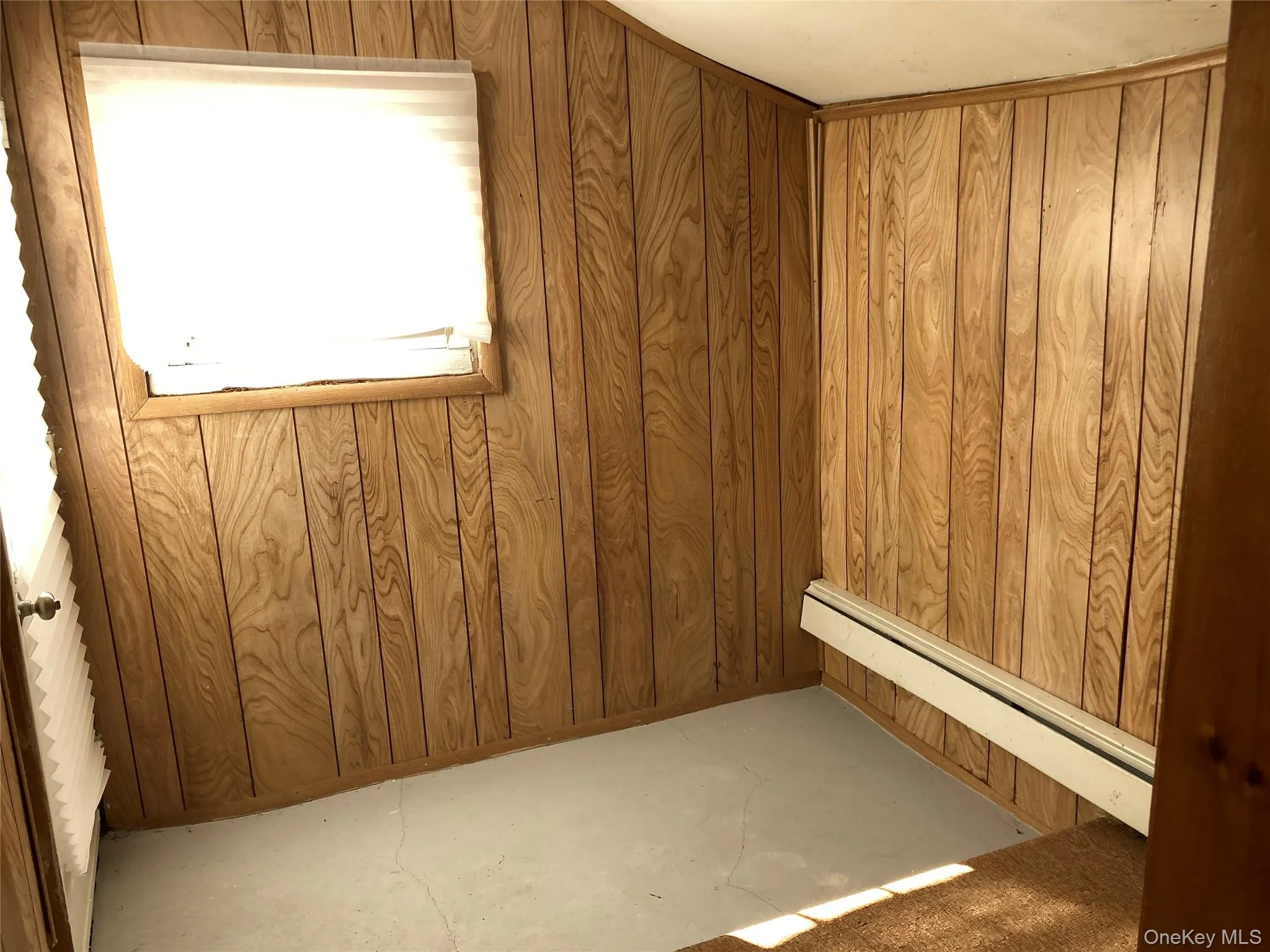 Below grade area with wood walls and a baseboard heating unit Below grade area with wood walls and a baseboard heating unit