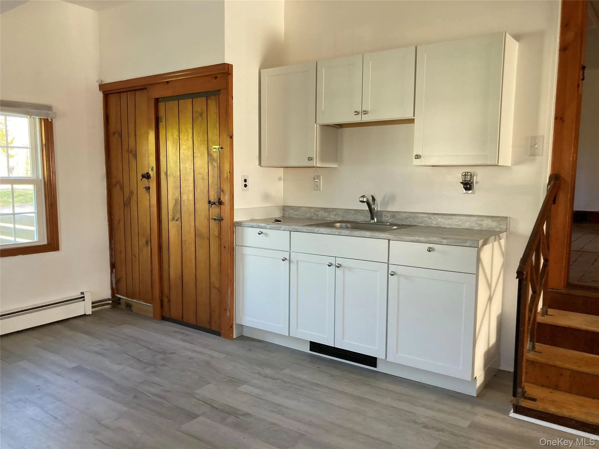 Kitchen with white cabinetry, light countertops, and light wood finished floors Kitchen with white cabinetry, light countertops, and light wood finished floors