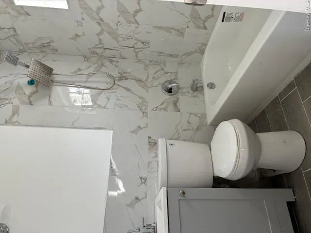 Bathroom with vanity, a combined bath / shower with marble appearance, and tile walls Bathroom with vanity, a combined bath / shower with marble appearance, and tile walls