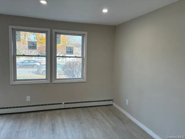 Unfurnished room featuring light wood-style flooring, a baseboard radiator, and recessed lighting Unfurnished room featuring light wood-style flooring, a baseboard radiator, and recessed lighting
