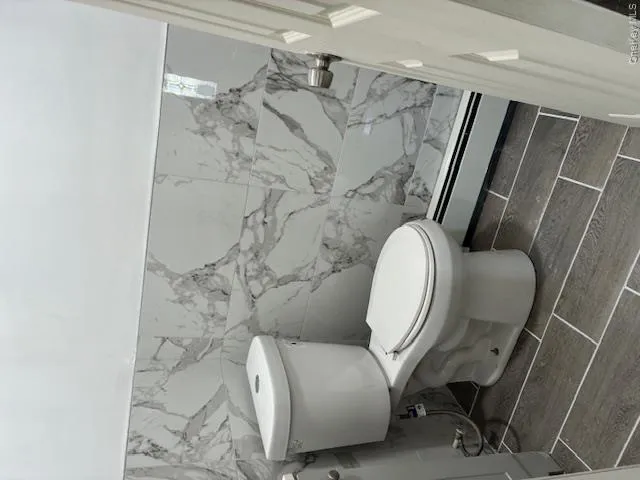 Bathroom featuring a baseboard heating unit, tile walls, wood tiled floors, and wainscoting Bathroom featuring a baseboard heating unit, tile walls, wood tiled floors, and wainscoting