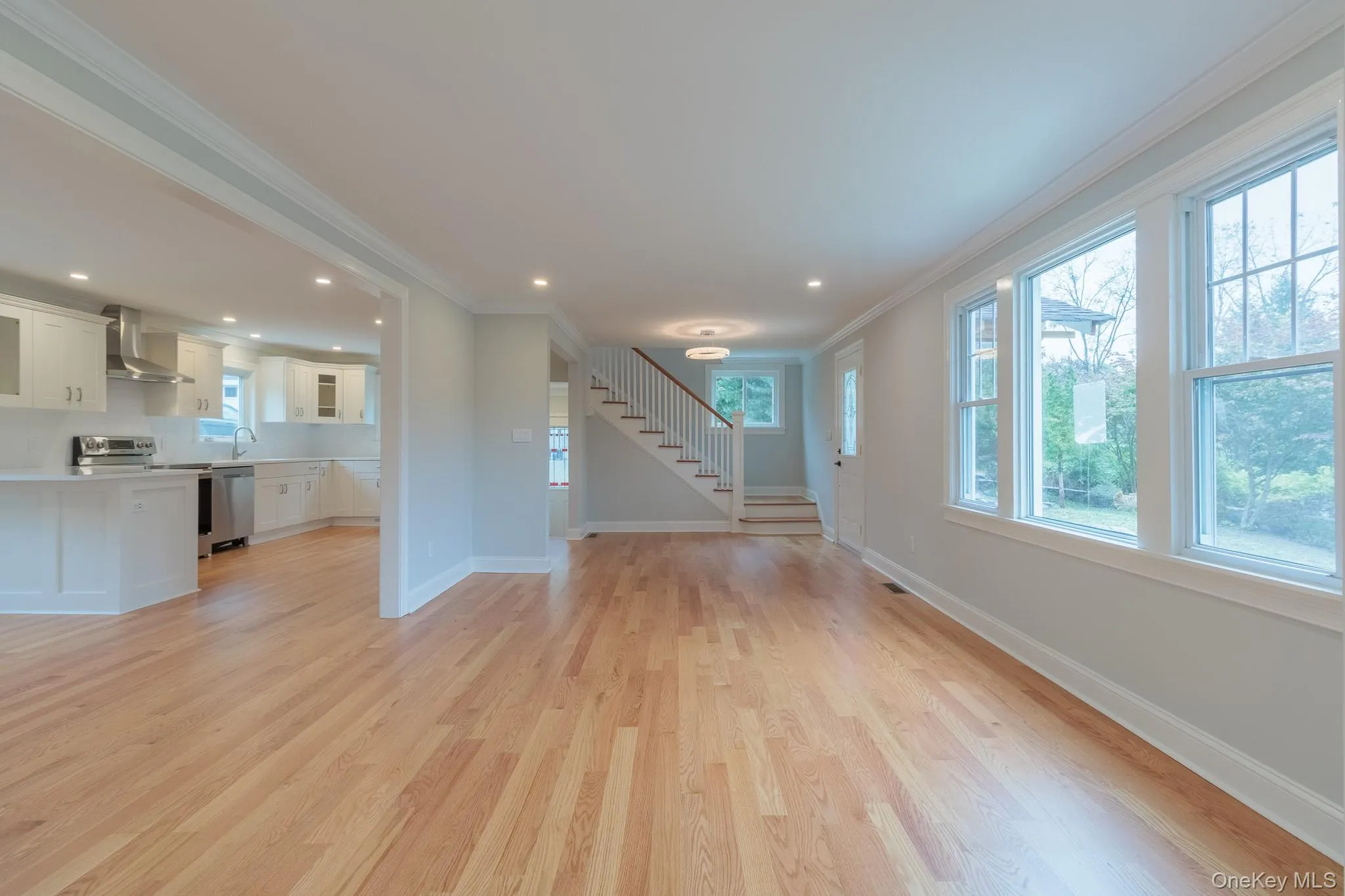 Unfurnished living room featuring crown molding, light wood-style floors, stairs, and recessed lighting Unfurnished living room featuring crown molding, light wood-style floors, stairs, and recessed lighting