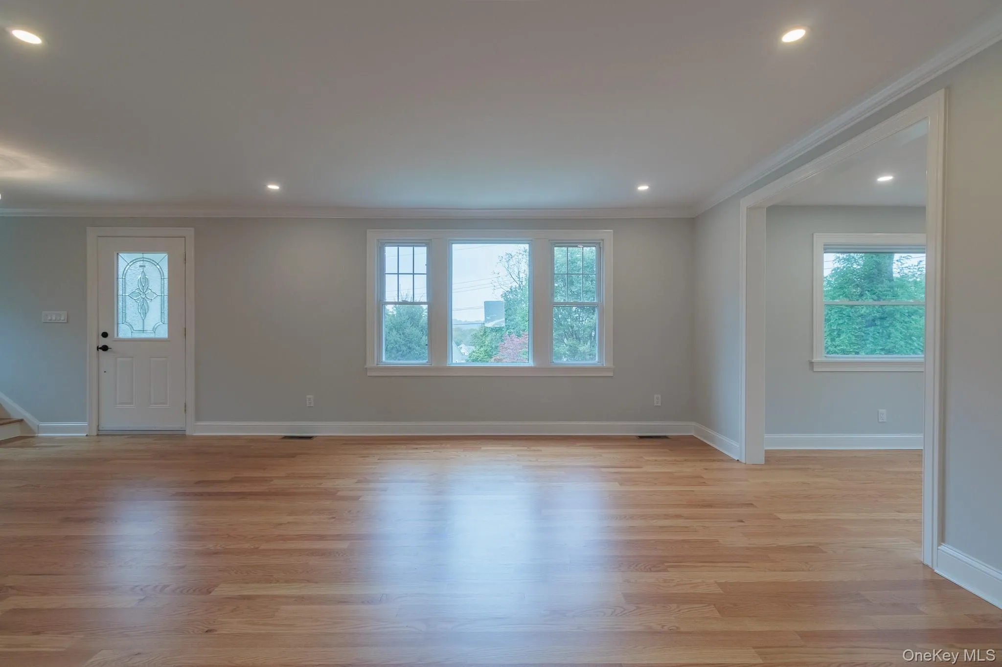 Unfurnished living room featuring ornamental molding, recessed lighting, light wood-style floors, and stairway Unfurnished living room featuring ornamental molding, recessed lighting, light wood-style floors, and stairway
