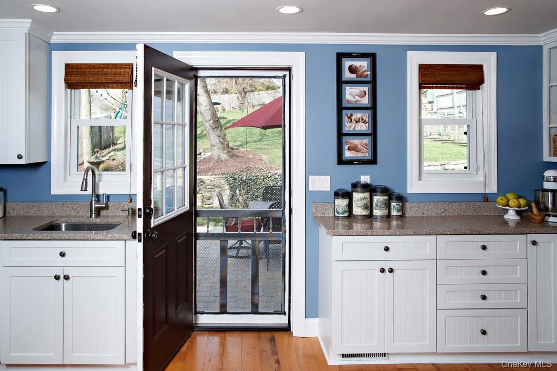 Kitchen featuring white cabinets, dark stone counters, light wood-type flooring, ornamental molding, and recessed lighting Kitchen featuring white cabinets, dark stone counters, light wood-type flooring, ornamental molding, and recessed lighting