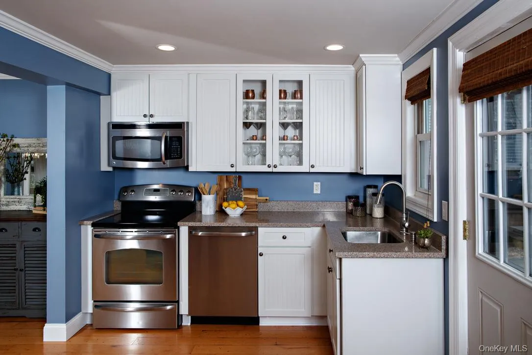 Kitchen with white cabinets, glass insert cabinets, appliances with stainless steel finishes, ornamental molding, and dark stone counters Kitchen with white cabinets, glass insert cabinets, appliances with stainless steel finishes, ornamental molding, and dark stone counters