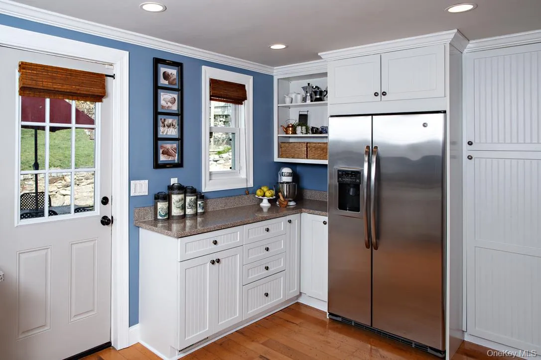 Kitchen with white cabinetry, stainless steel fridge, open shelves, light wood-type flooring, and recessed lighting Kitchen with white cabinetry, stainless steel fridge, open shelves, light wood-type flooring, and recessed lighting