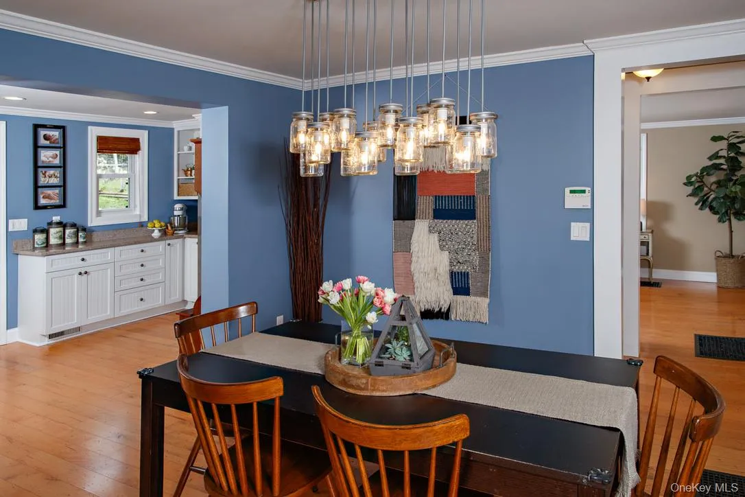 Dining space with crown molding, light wood-style flooring, and a chandelier Dining space with crown molding, light wood-style flooring, and a chandelier