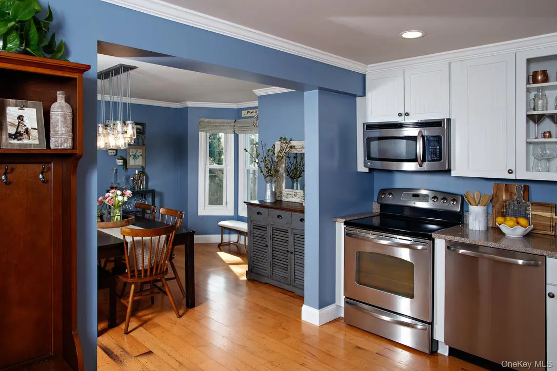 Kitchen with stainless steel appliances, glass insert cabinets, crown molding, white cabinetry, and light wood-type flooring Kitchen with stainless steel appliances, glass insert cabinets, crown molding, white cabinetry, and light wood-type flooring