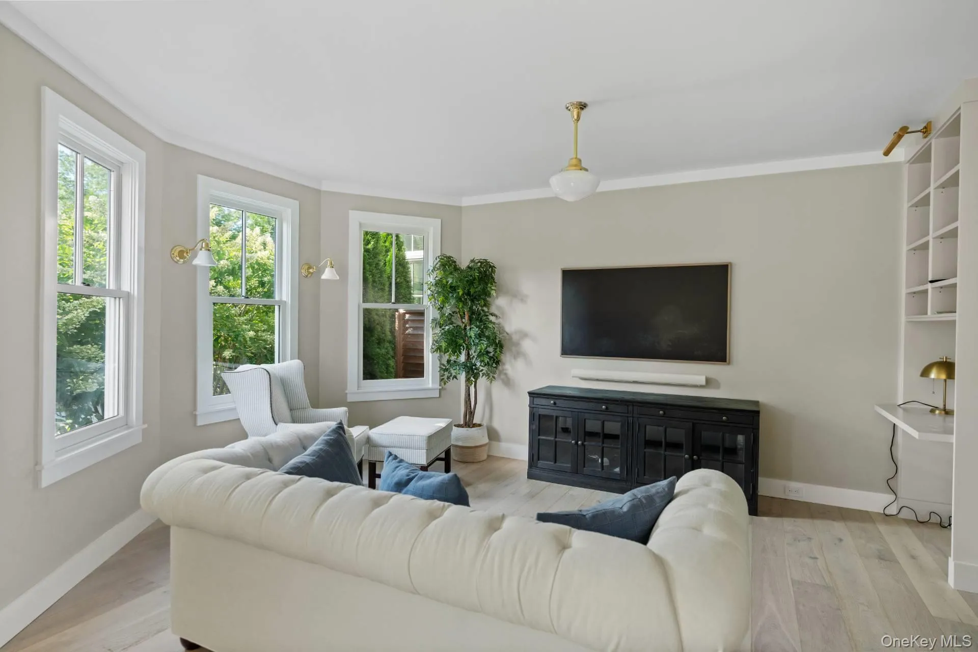 Living area with healthy amount of natural light, light wood-style flooring, and crown molding Living area with healthy amount of natural light, light wood-style flooring, and crown molding