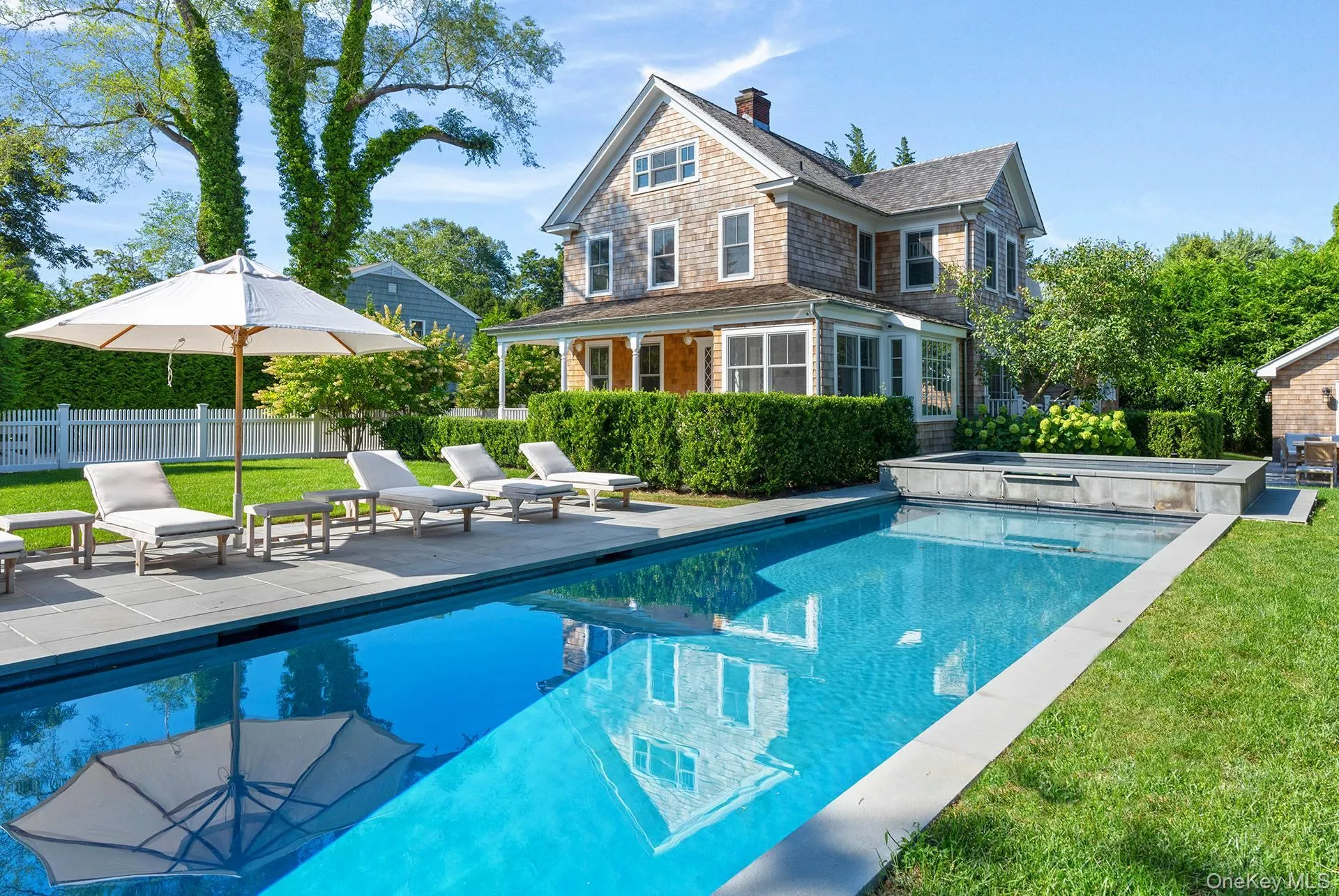 Rear view of house with a patio area, a chimney, and a pool with connected hot tub Rear view of house with a patio area, a chimney, and a pool with connected hot tub