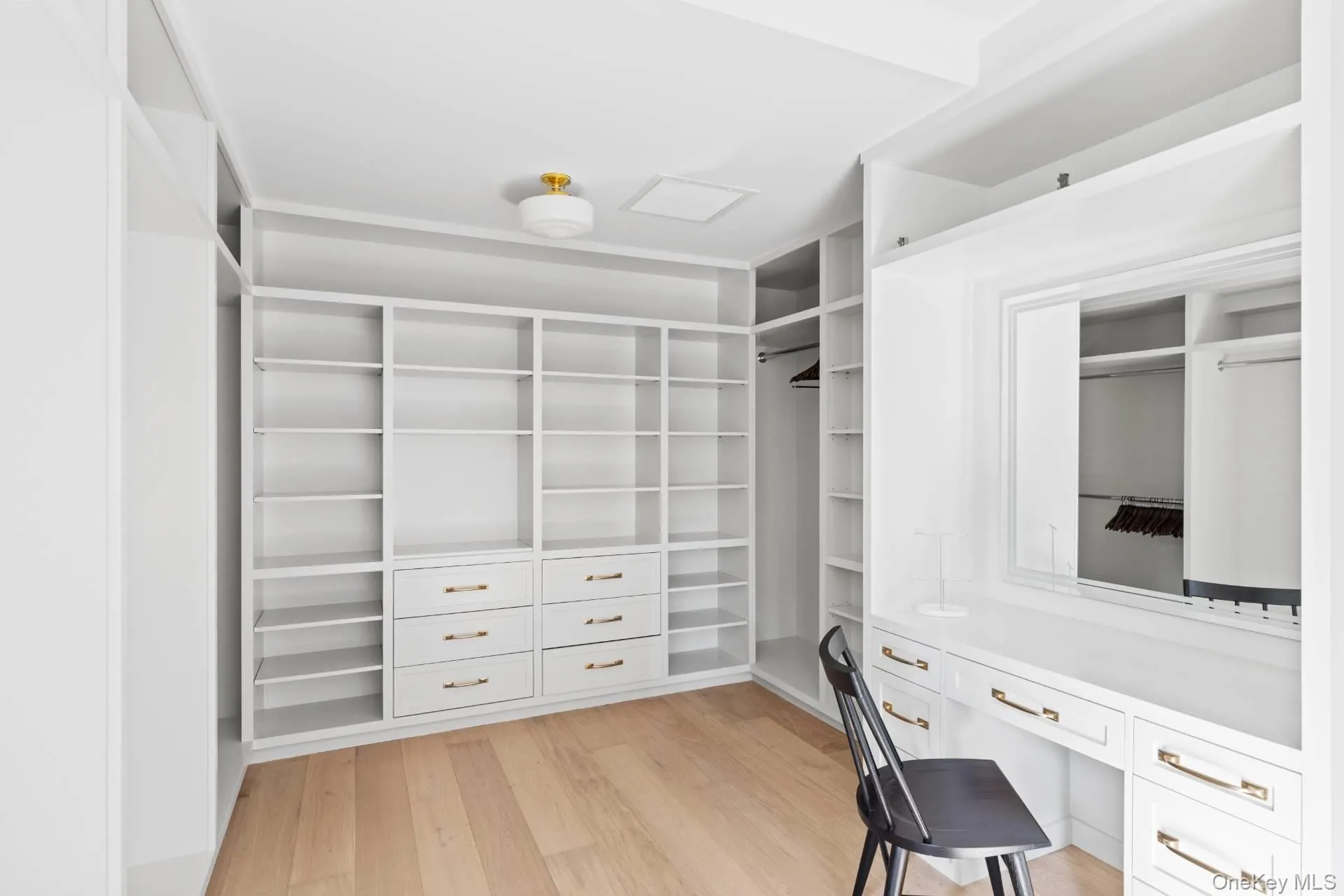 Spacious closet featuring built in desk and light wood finished floors Spacious closet featuring built in desk and light wood finished floors