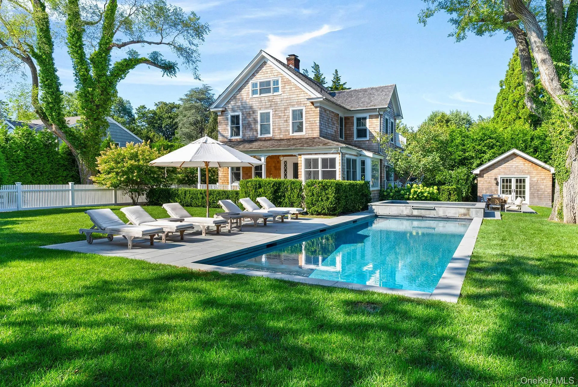 Rear view of house with a patio, a chimney, an outbuilding, a storage structure, and a pool with connected hot tub Rear view of house with a patio, a chimney, an outbuilding, a storage structure, and a pool with connected hot tub