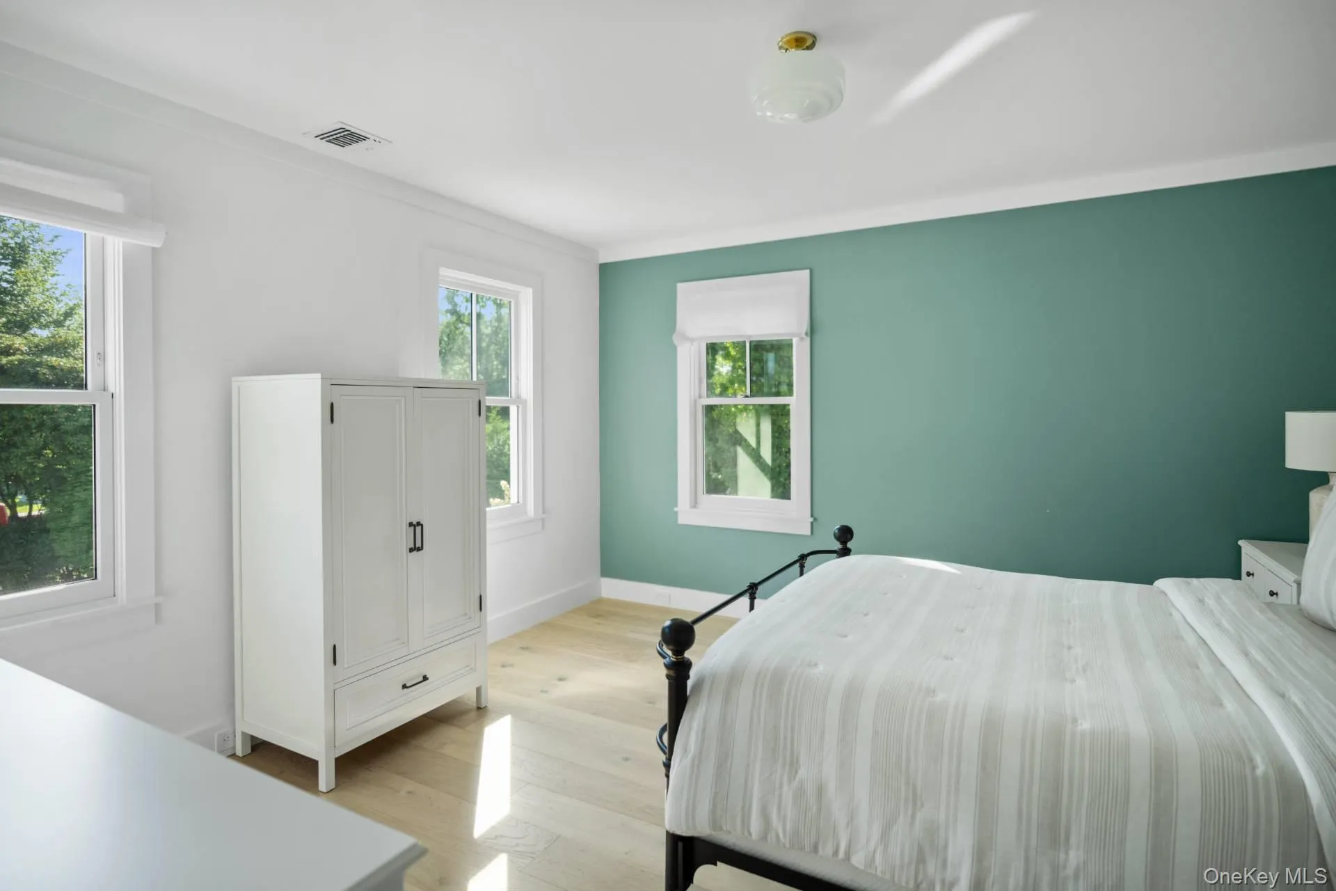 Bedroom with light wood-style flooring and ornamental molding Bedroom with light wood-style flooring and ornamental molding