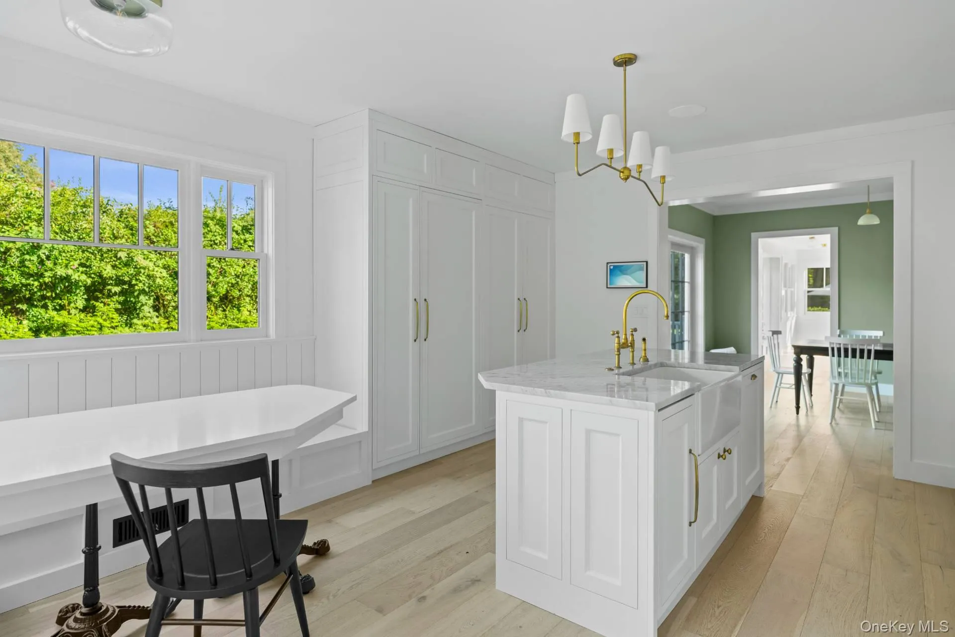 Kitchen featuring white cabinets, light stone countertops, light wood-type flooring, and healthy amount of natural light Kitchen featuring white cabinets, light stone countertops, light wood-type flooring, and healthy amount of natural light