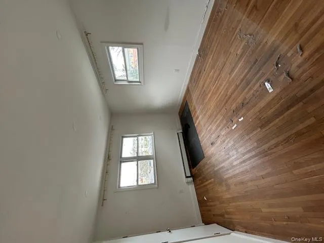 Empty room with a baseboard radiator and hardwood / wood-style flooring Empty room with a baseboard radiator and hardwood / wood-style flooring