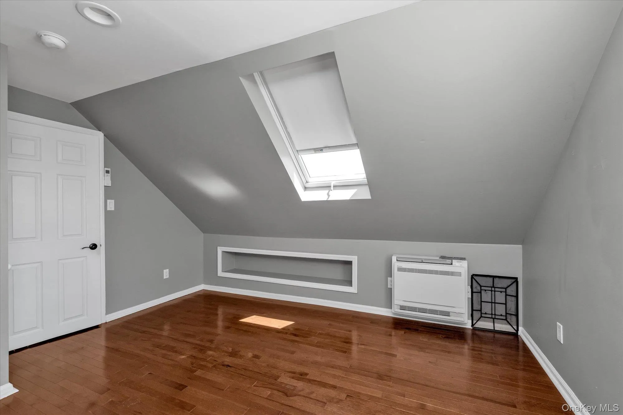 Bonus room featuring a skylight, heating unit, dark wood-style floors, and vaulted ceiling Bonus room featuring a skylight, heating unit, dark wood-style floors, and vaulted ceiling
