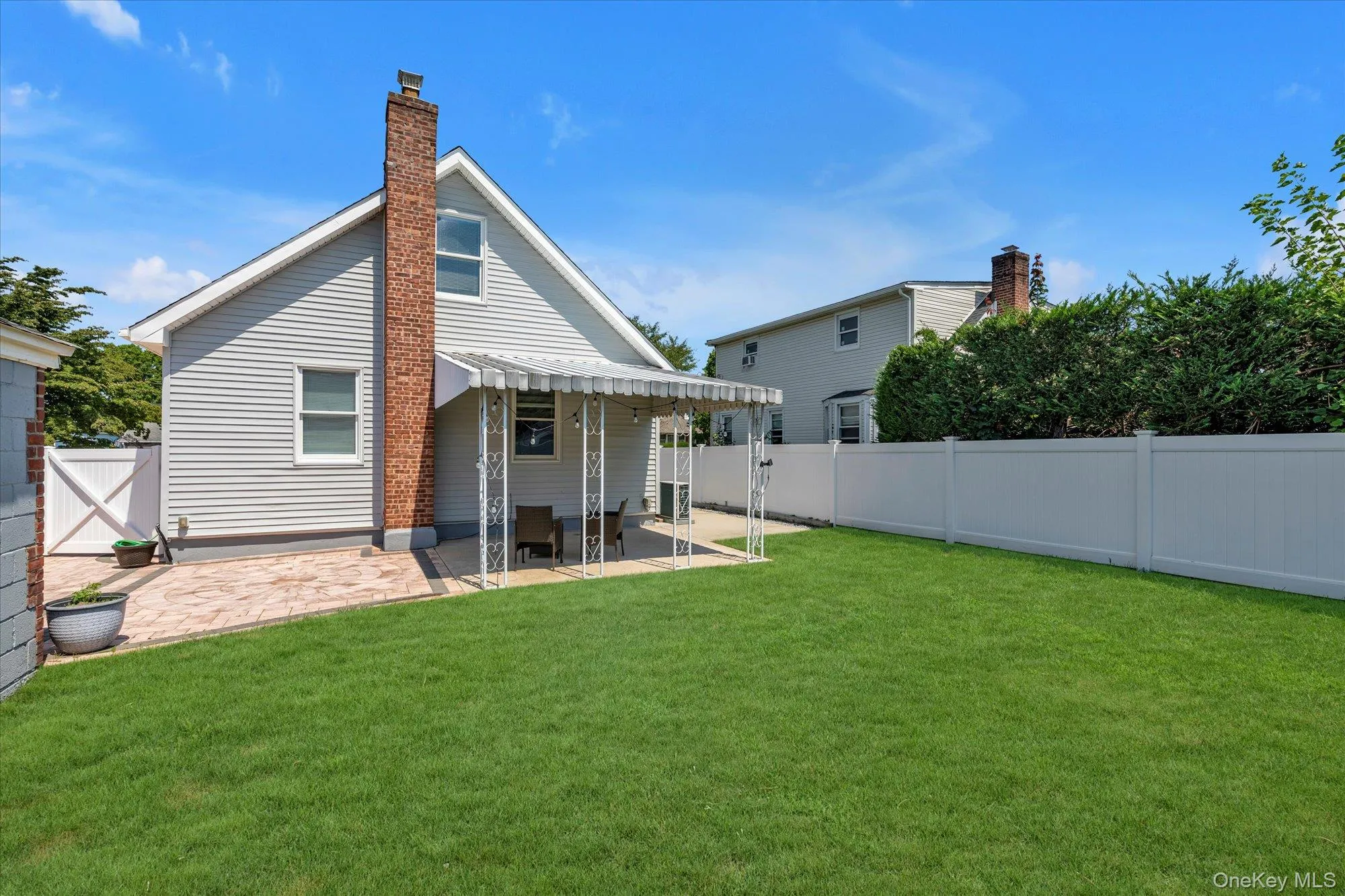 Back of property featuring a patio, a fenced backyard, a gate, and a chimney Back of property featuring a patio, a fenced backyard, a gate, and a chimney