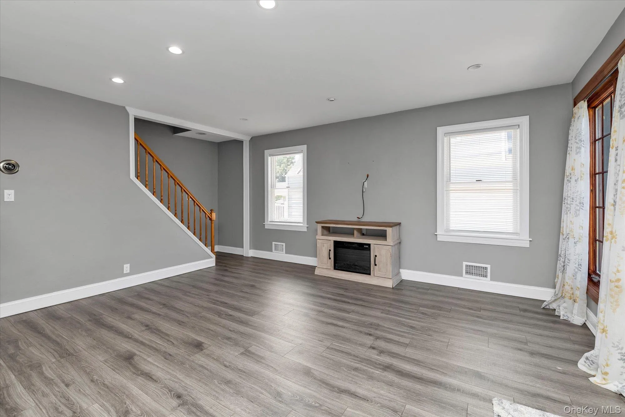 Unfurnished living room with wood finished floors, stairway, recessed lighting, and a fireplace Unfurnished living room with wood finished floors, stairway, recessed lighting, and a fireplace