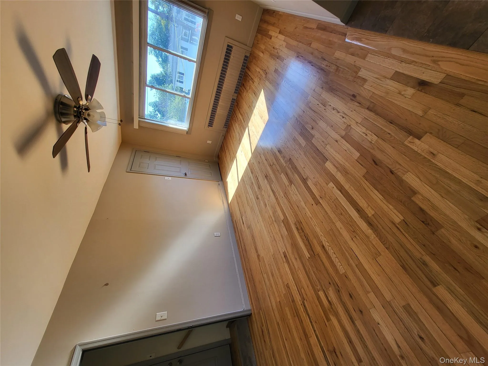 Spare room with radiator, hardwood / wood-style flooring, and ceiling fan Spare room with radiator, hardwood / wood-style flooring, and ceiling fan