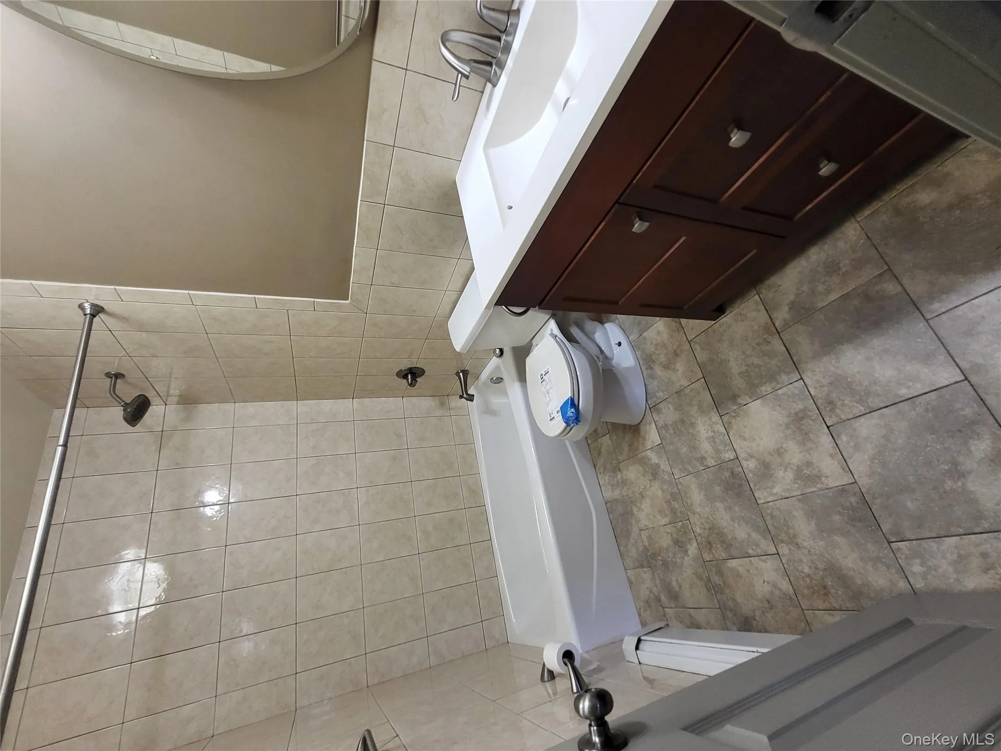Bathroom featuring vanity, bathing tub / shower combination, tile walls, and dark tile patterned flooring Bathroom featuring vanity, bathing tub / shower combination, tile walls, and dark tile patterned flooring