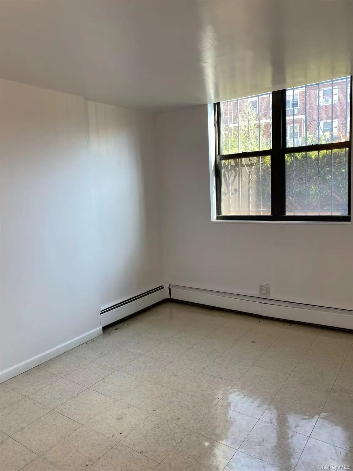 Empty room featuring a baseboard heating unit and light floors Empty room featuring a baseboard heating unit and light floors