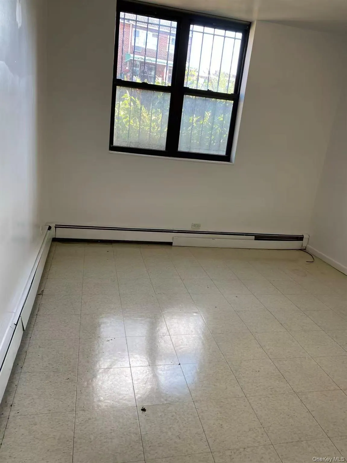 Empty room with light floors and a baseboard radiator Empty room with light floors and a baseboard radiator