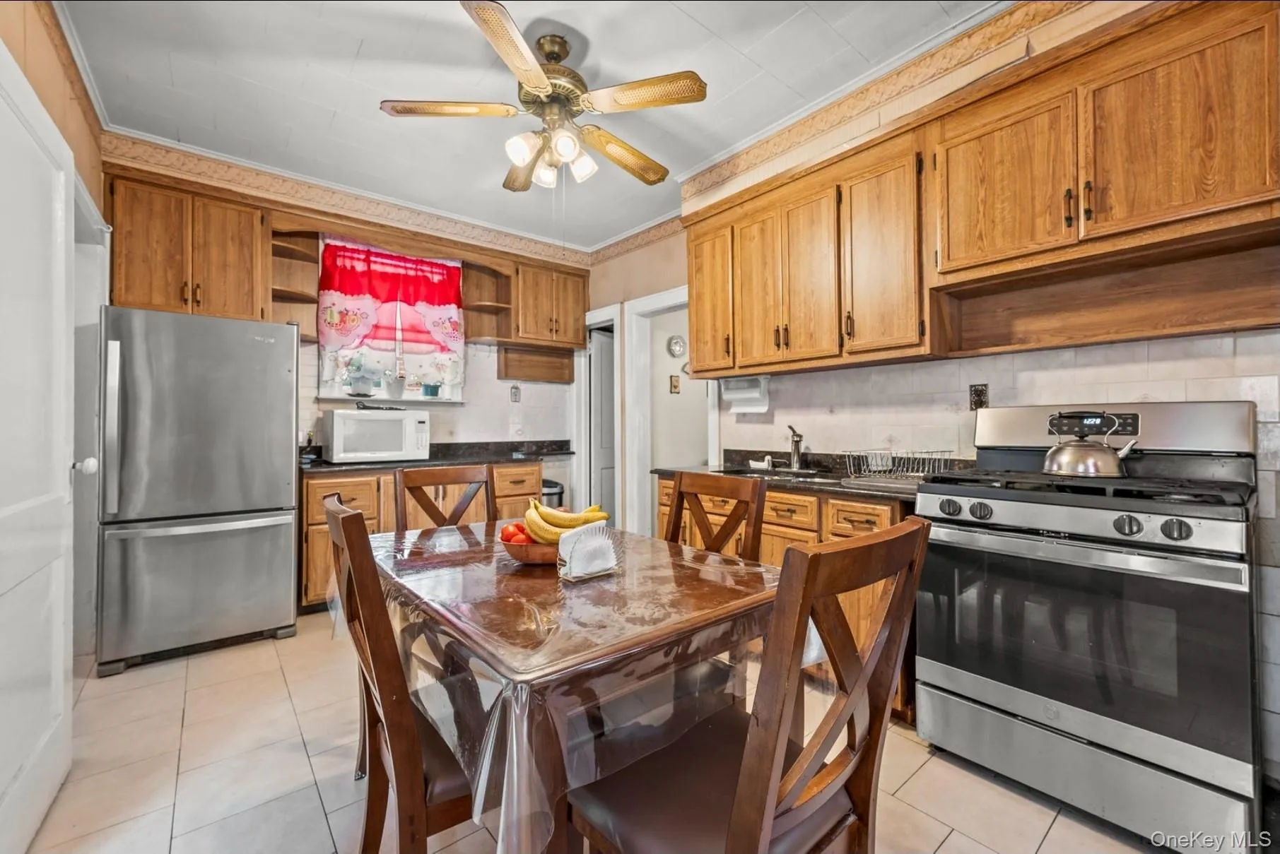 Kitchen with open shelves, stainless steel appliances, brown cabinets, decorative backsplash, and crown molding Kitchen with open shelves, stainless steel appliances, brown cabinets, decorative backsplash, and crown molding