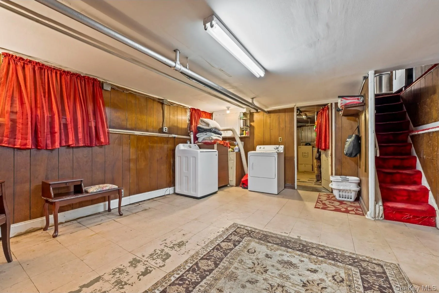 Finished basement featuring washer and clothes dryer, wood walls, and stairs Finished basement featuring washer and clothes dryer, wood walls, and stairs