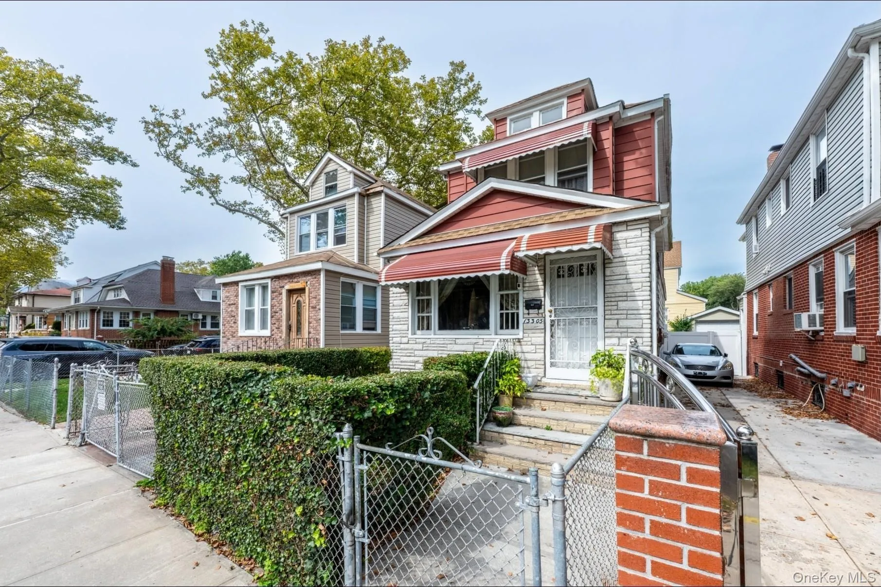 American foursquare style home featuring a gate, stone siding, and a fenced front yard American foursquare style home featuring a gate, stone siding, and a fenced front yard