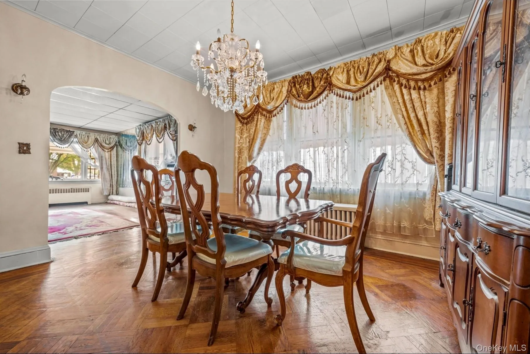 Dining area featuring arched walkways, a chandelier, and radiator Dining area featuring arched walkways, a chandelier, and radiator