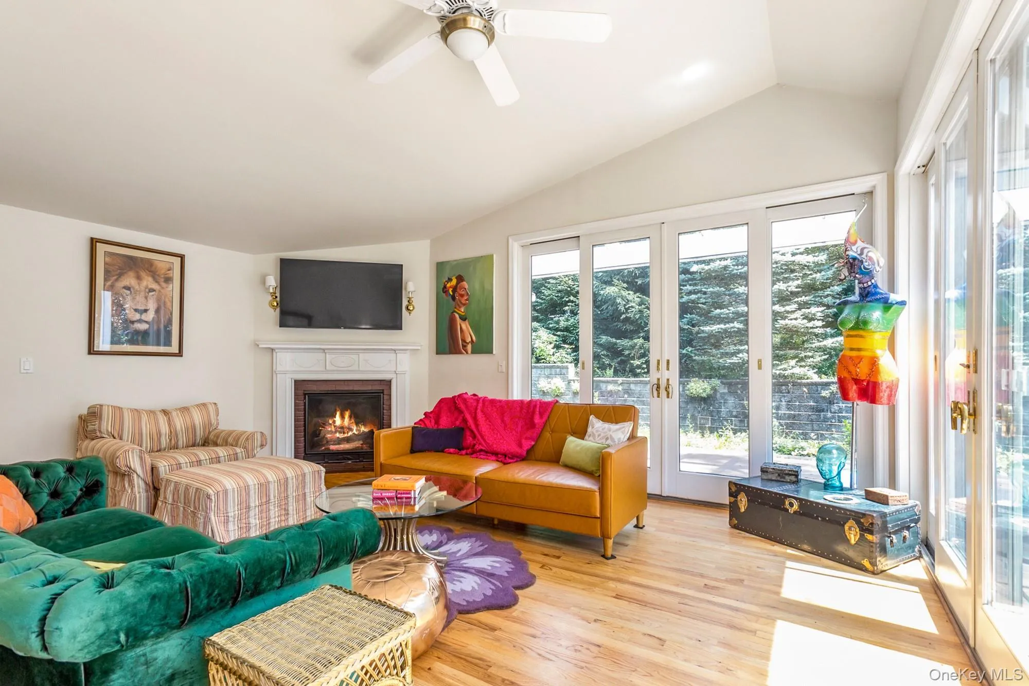 Living area with french doors, lofted ceiling, wood finished floors, a fireplace, and a ceiling fan Living area with french doors, lofted ceiling, wood finished floors, a fireplace, and a ceiling fan
