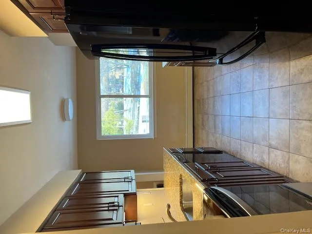 Kitchen featuring dark brown cabinets, light stone countertops, fridge, stove, and light tile patterned flooring Kitchen featuring dark brown cabinets, light stone countertops, fridge, stove, and light tile patterned flooring