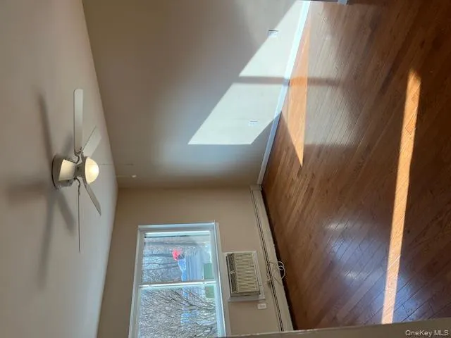 Unfurnished room featuring light wood-style flooring, a baseboard heating unit, a ceiling fan, and a wall mounted AC Unfurnished room featuring light wood-style flooring, a baseboard heating unit, a ceiling fan, and a wall mounted AC