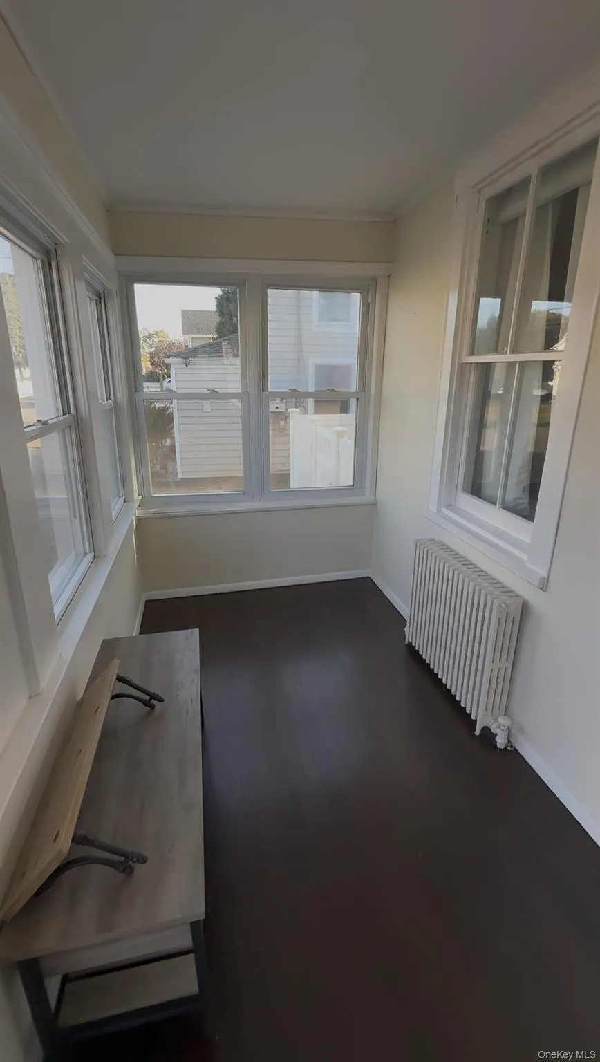 Unfurnished sunroom featuring radiator heating unit and wood finished floors Unfurnished sunroom featuring radiator heating unit and wood finished floors