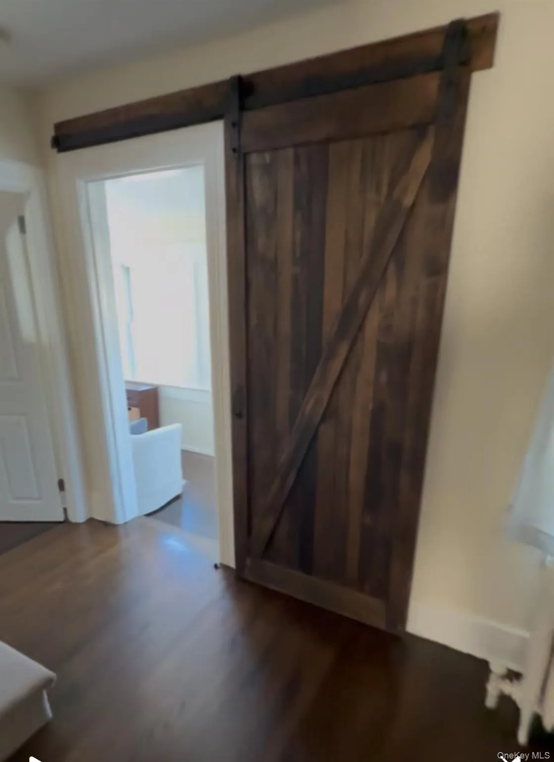 Corridor featuring dark wood finished floors, a barn door, and radiator Corridor featuring dark wood finished floors, a barn door, and radiator