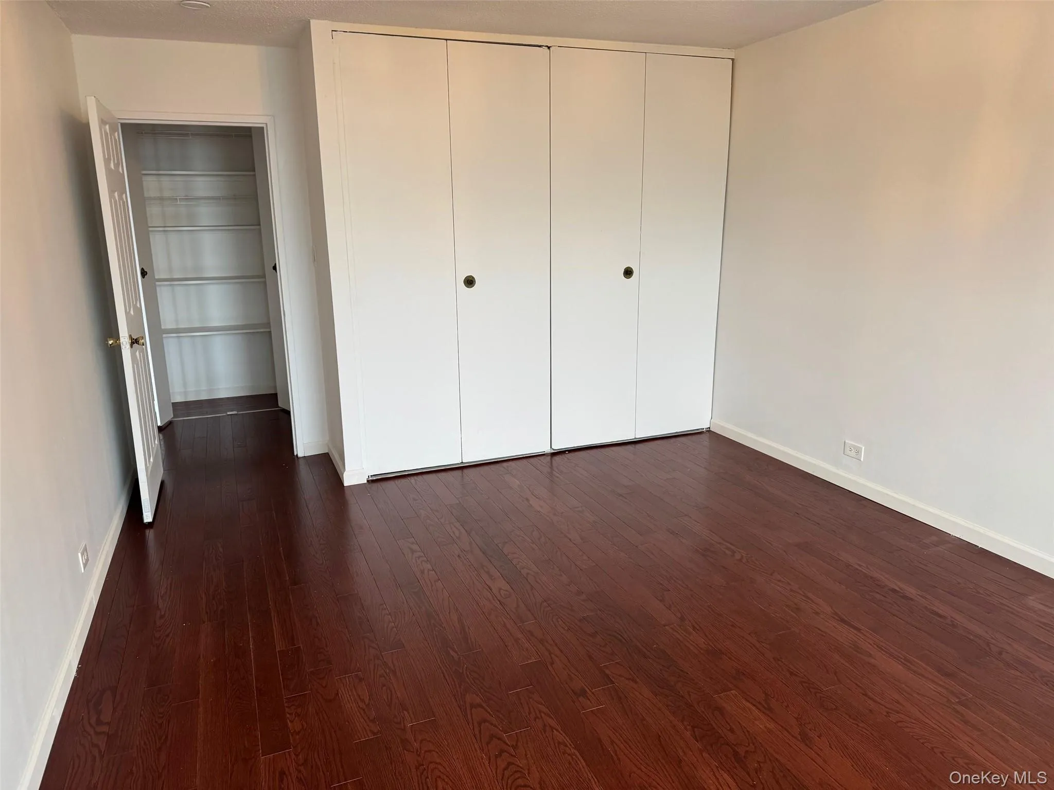 Unfurnished bedroom featuring dark wood-type flooring and a closet Unfurnished bedroom featuring dark wood-type flooring and a closet