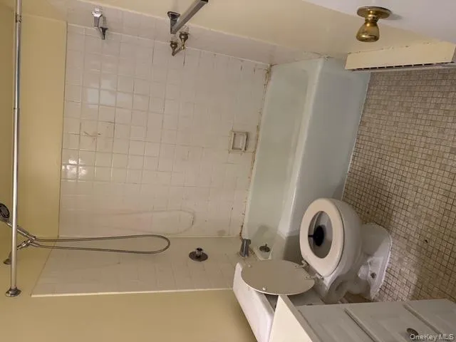 Bathroom with  shower combination, vanity, baseboard heating, and light tile patterned floors Bathroom with  shower combination, vanity, baseboard heating, and light tile patterned floors