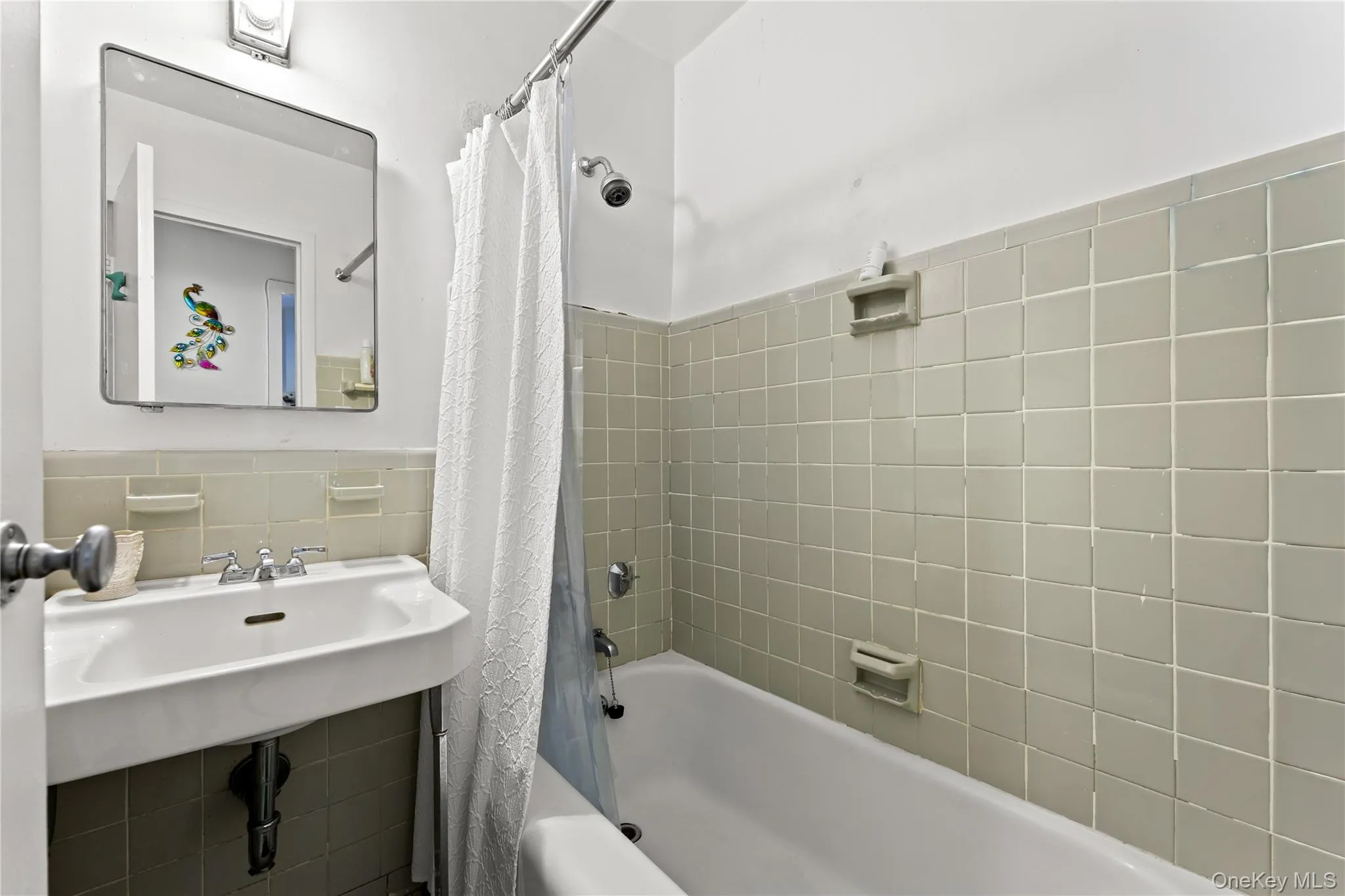 Full bath featuring shower / tub combo with curtain, tile walls, and wainscoting Full bath featuring shower / tub combo with curtain, tile walls, and wainscoting